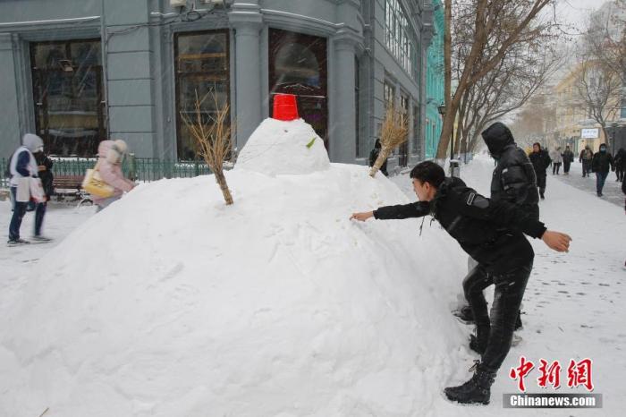 資料圖：11月19日，黑龍江省哈爾濱市迎來大暴雪天氣，雖給當地市民交通出行帶來不便，但也營造了銀裝素裹的冬季美景。 圖為中央大街上的雪人吸引遊客。 中新社記者呂品攝